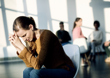 young-sad-woman-sitting-apart-from-attenders-group-therapy-community-center